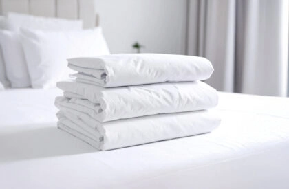 Nettoyage linges plats : pile de draps blancs soigneusement pliés sur un lit d’hôtel